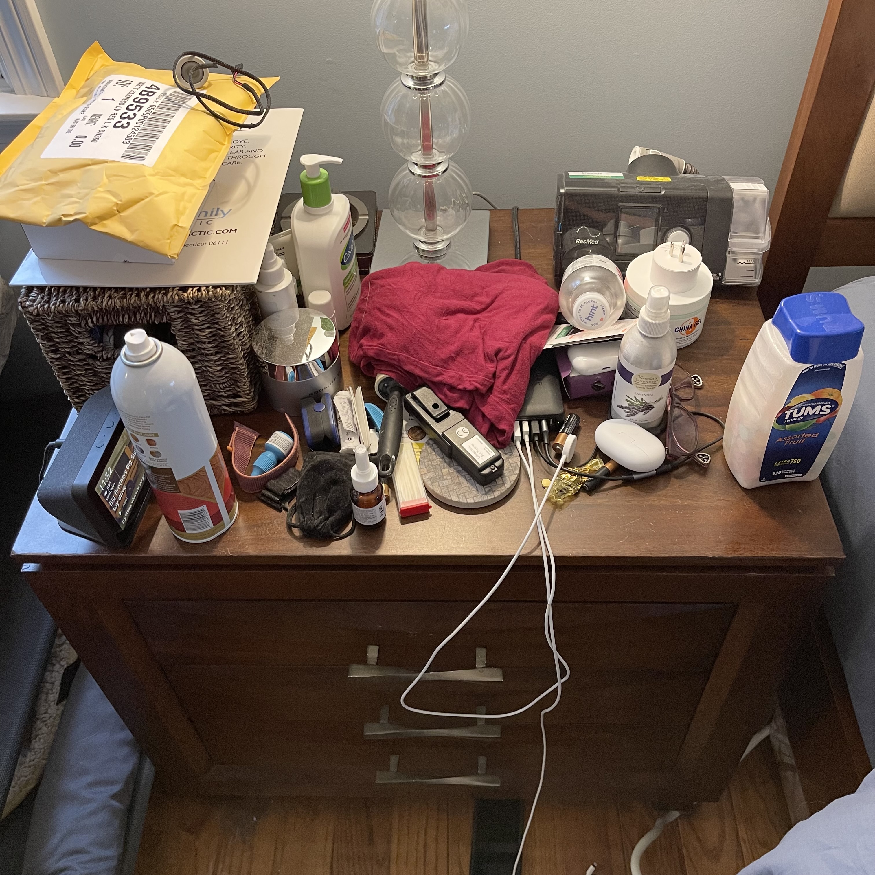 A messy end table with a bunch of miscellaneous items on it.